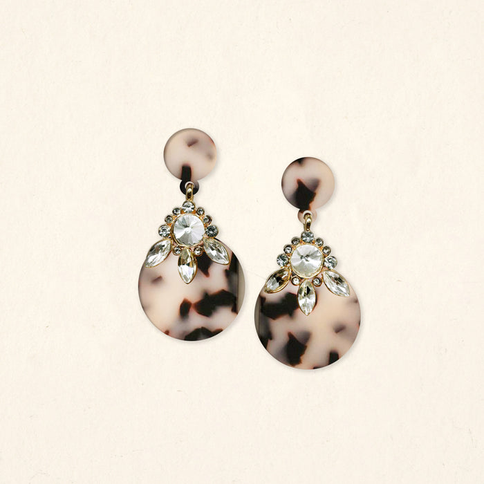The Darling Effect's Blonde Tortoise Show Stopper Earrings feature round tortoiseshell-patterned acetate discs with clear crystals and marquise-shaped rhinestones in a floral design, set against a plain light background.