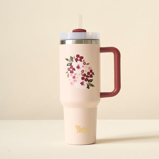 The Buds & Bloom Blush 40oz Take Me Everywhere Tumbler by The Darling Effect is a pink floral tumbler with a maroon handle, straw, and gold “the darling effect” text on the bottom.