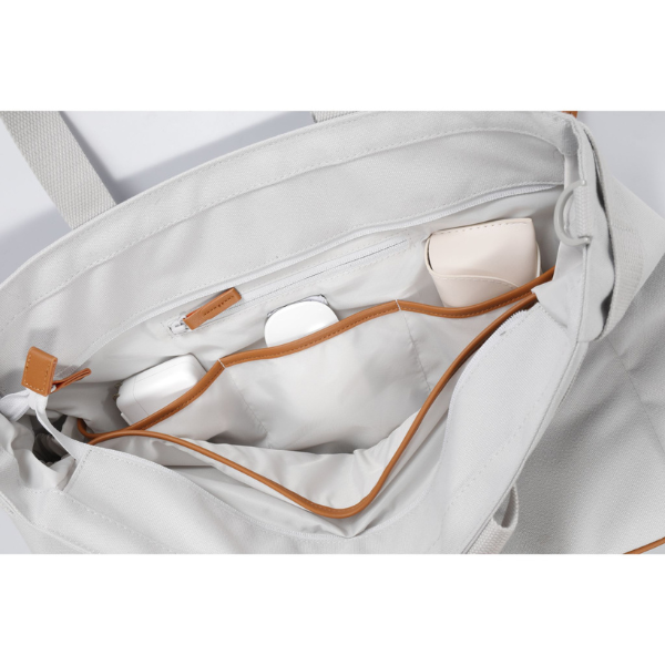 Close-up of a light gray bag with brown accents and a white device inside.
