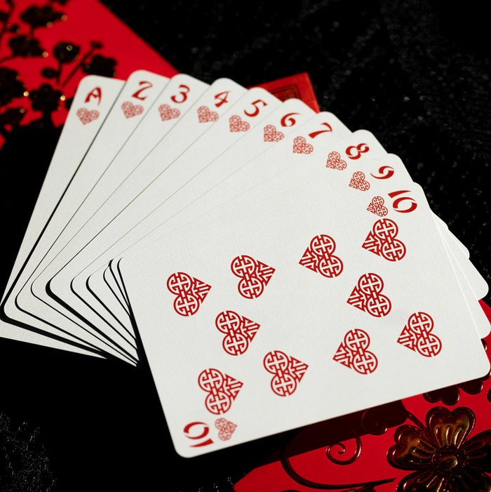 Playing cards with red suits on a black and red floral background