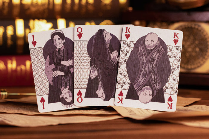 Four playing cards featuring different characters on a wooden surface with a blurred background.