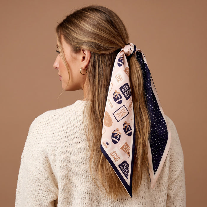 A woman with long, light brown hair wears a cream sweater and The Darling Effect’s Huddle Up Twirl & Tie Scarf Accessory, styled in her hair and viewed from behind against a neutral beige background.