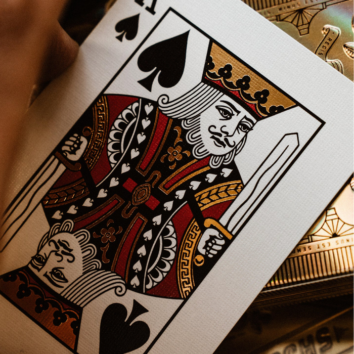 Close-up of a playing card with a detailed design, likely a queen of spades, held by a hand.