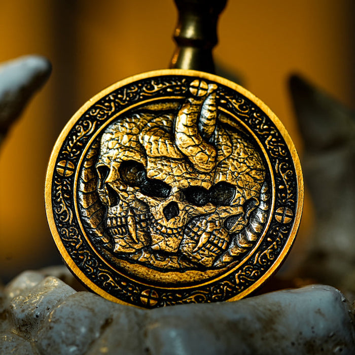 Decorative gold coin with skull and snake design on a stone surface