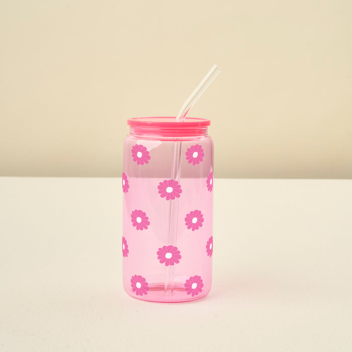 The Darling Effect Pink Color Glass Round Cup with pink daisy details, a matching pink lid, and a glass straw rests on a white surface against a beige background.