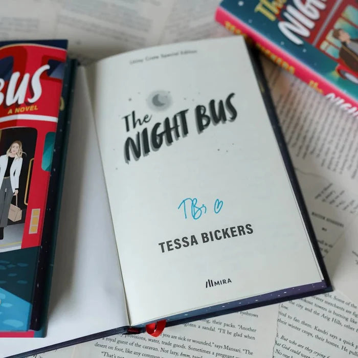 Signed title page of The Night Bus LitJoy Crate Special Edition hardcover, showing the title in stylized font, Tessa Bickers blue ink autograph signature, her printed name, and the MIRA publisher logo. The paperback and LitJoy hardcover editions are visible around it on a bed of open book pages.