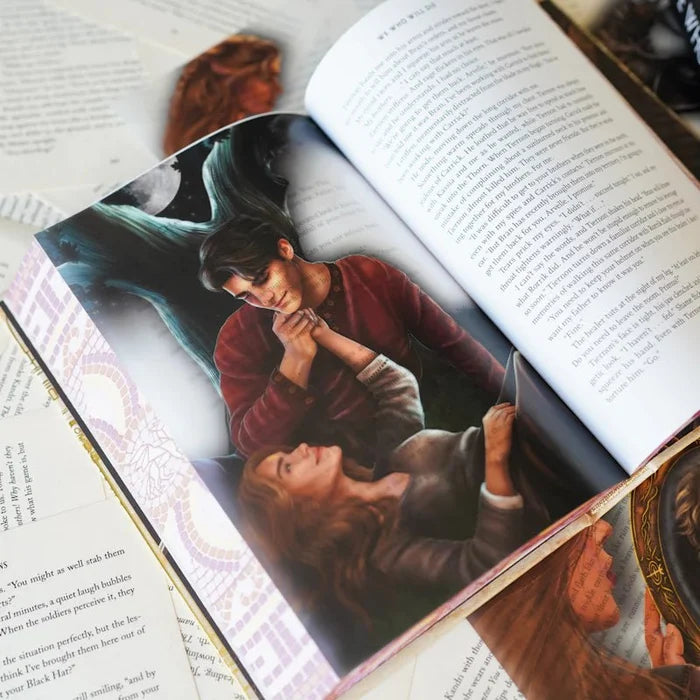 We Who Will Die LitJoy Edition page overlay inside the open book, showing a dark-haired man holding a woman's hand with a ghostly figure in a moonlit background, with the mosaic book spine and another overlay card visible nearby